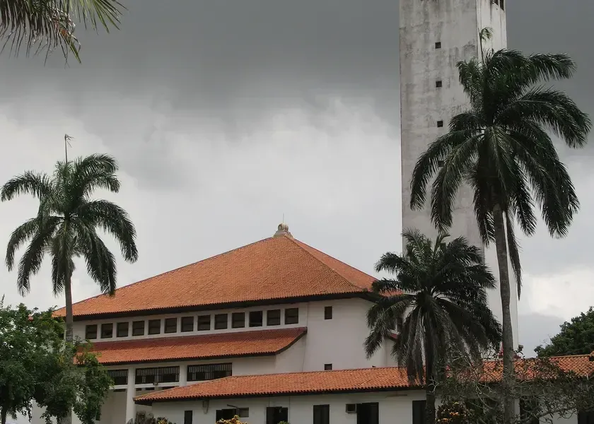 A tall white clock tower on the University of Ghana campus