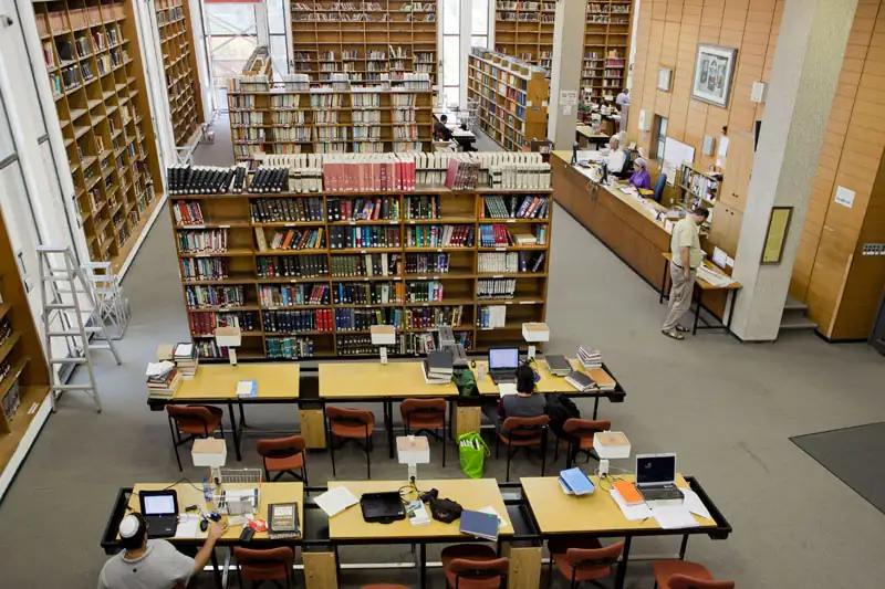 Adults reading and working at tables in a library