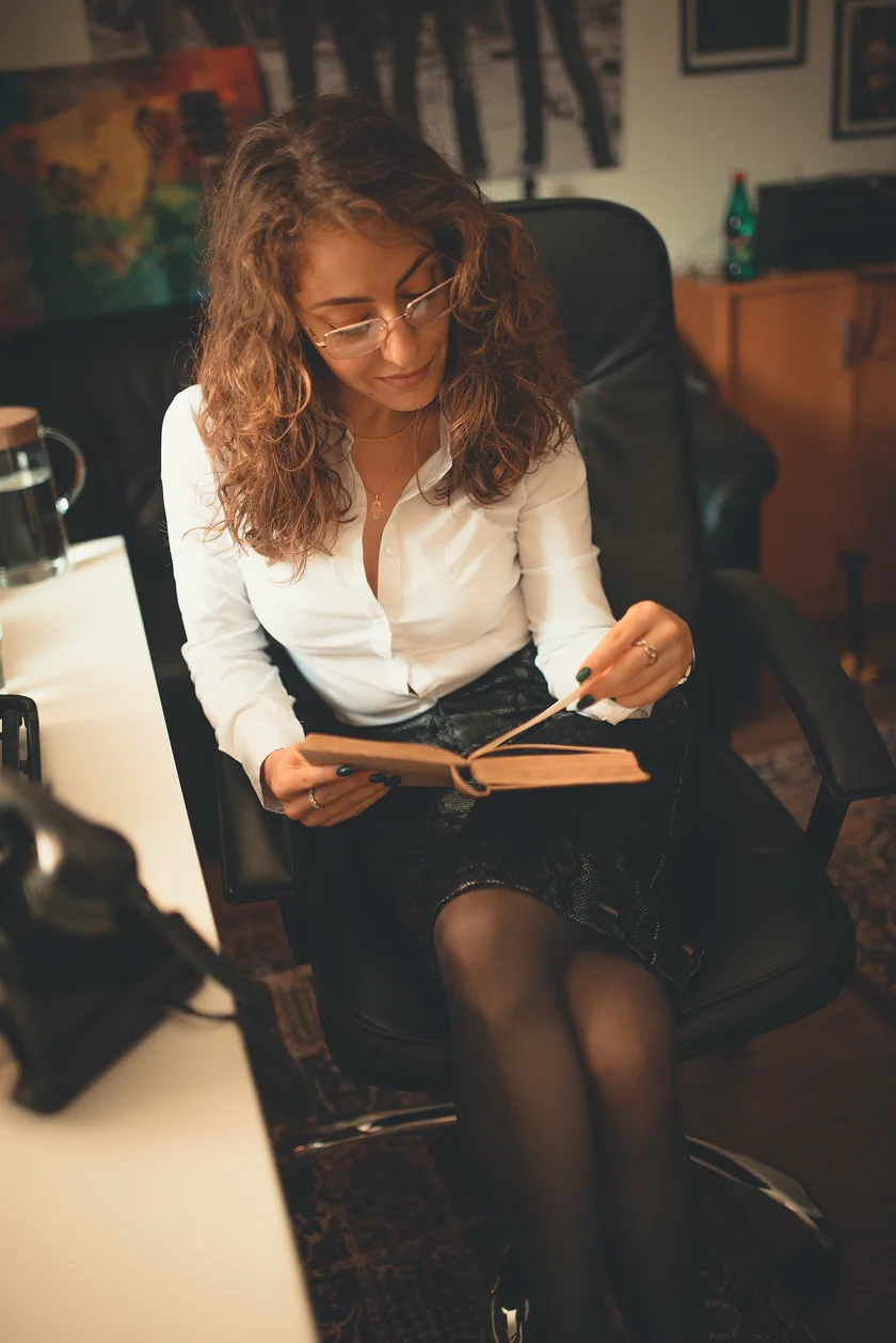 A woman sitting in an office chair and reading an open book