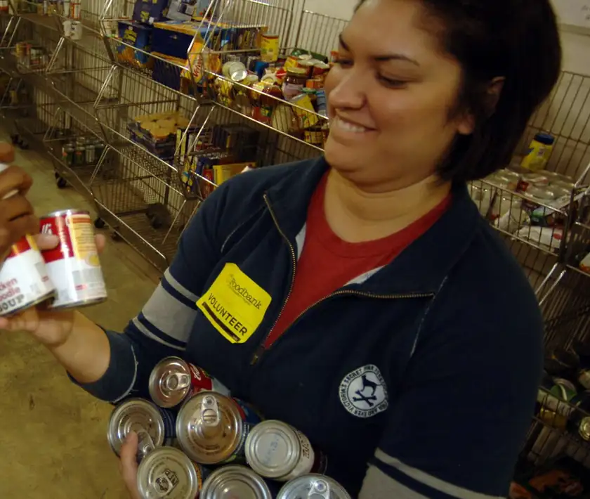 A volunteer holding several cans of donated food
