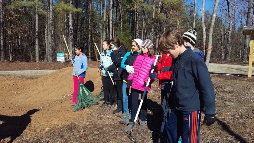 Teen volunteers in yellow vests working outdoors on a service project
