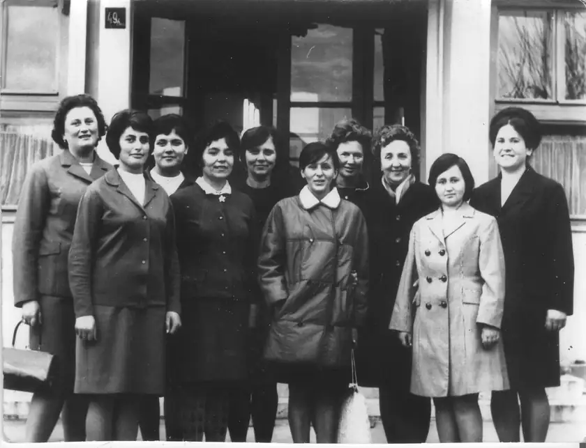 A black-and-white photo of a group of women standing together outside a school doorway