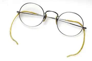 A pair of antique round spectacles with thin metal frames on a gray background