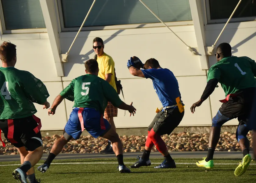 Adults playing flag football on a turf field