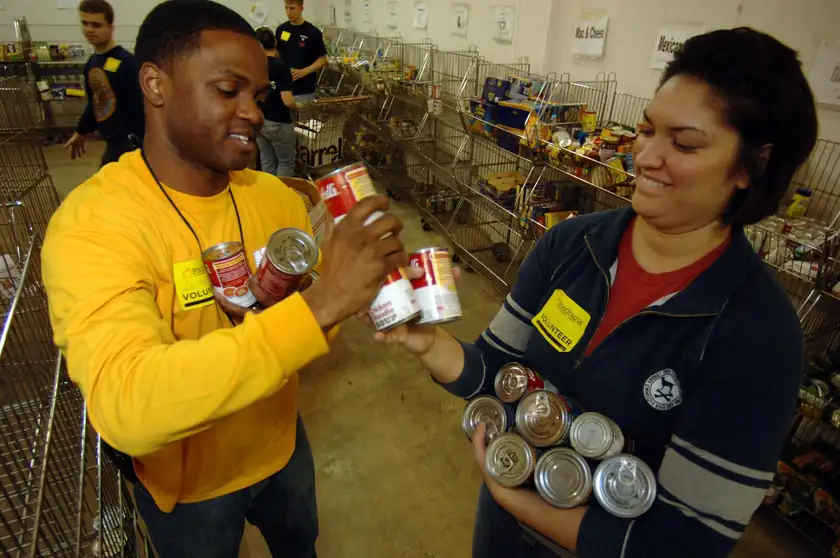 Two adult volunteers sorting canned food at a food bank