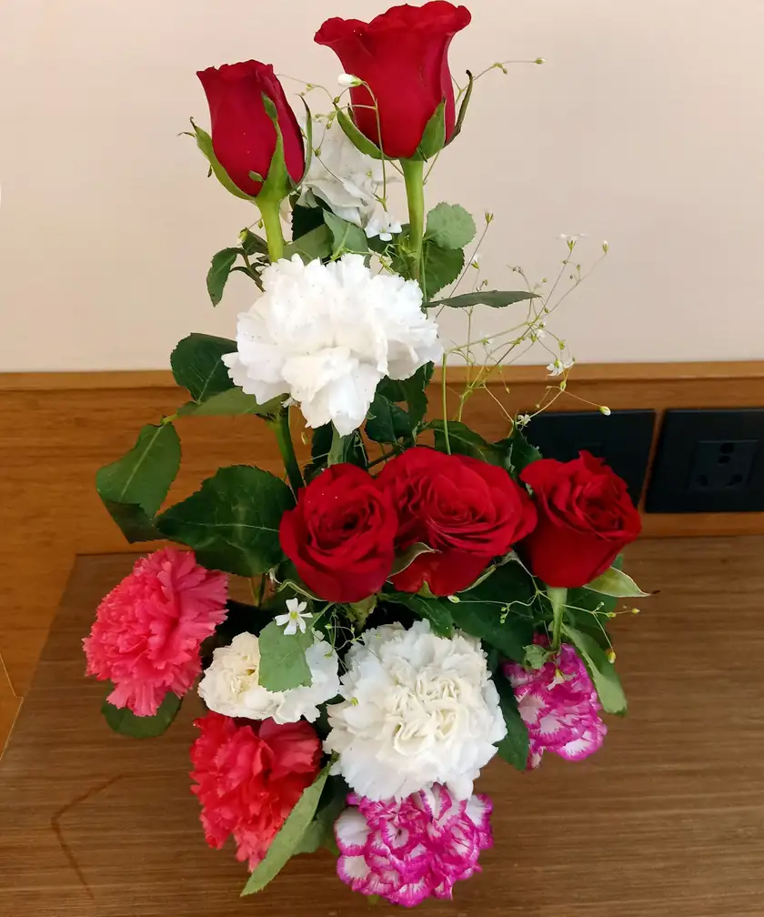 A bouquet of red roses and white carnations wrapped in paper