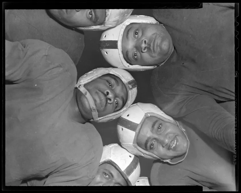 Football players in a huddle, photographed from below