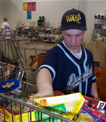 A young man sorting boxes of donated groceries into a cart