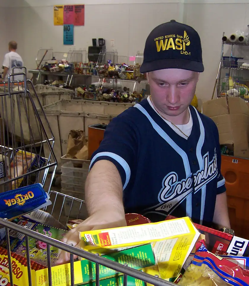 A young man sorting boxes of donated groceries into a cart