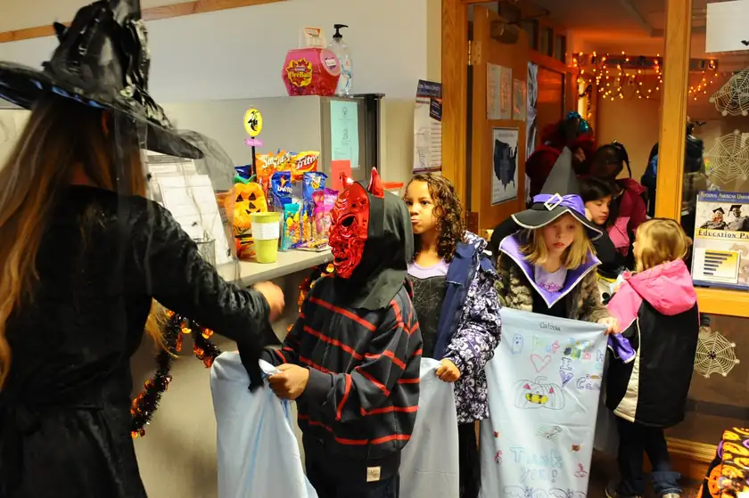 An adult in a Halloween costume holding a bag of candy