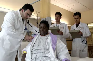 A doctor using a stethoscope on an adult patient's back