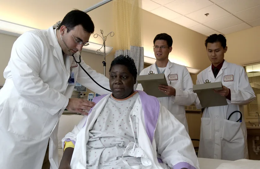 A doctor using a stethoscope on an adult patient's back