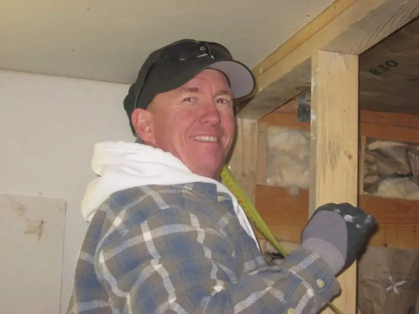 Volunteers framing a house with lumber at a building site