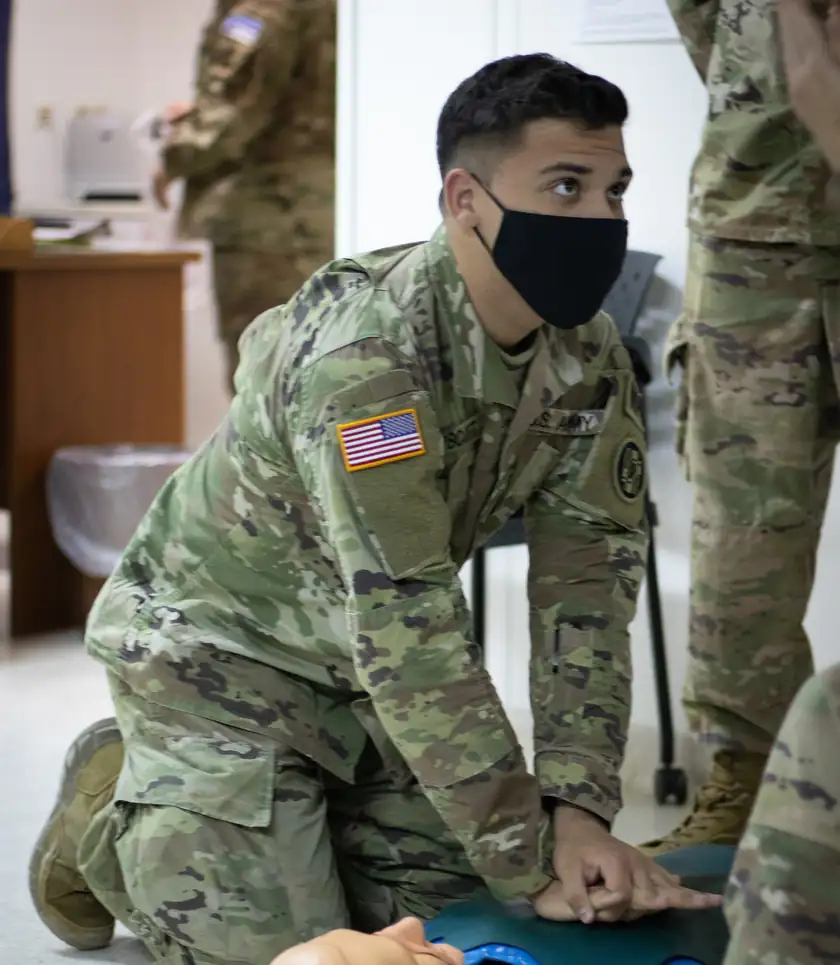 A soldier practicing chest compressions on a CPR training manikin