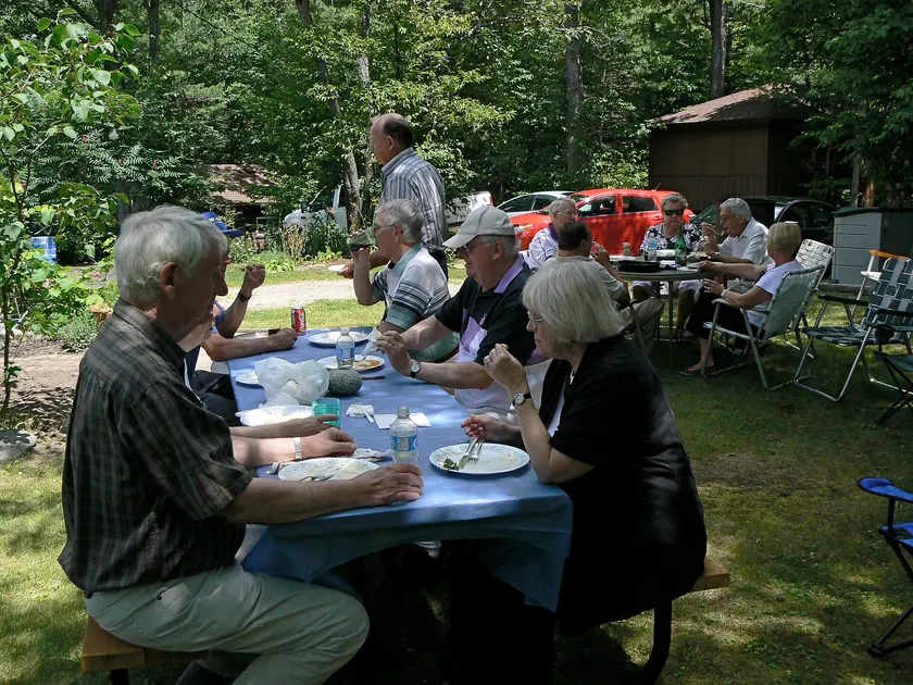 People serving themselves from bowls of food at a long buffet table