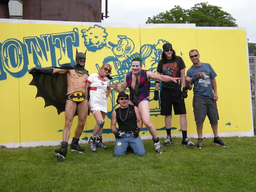 Adults in homemade superhero costumes marching in a daytime parade
