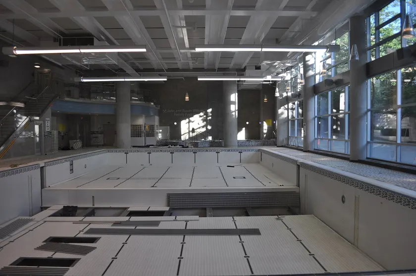 An indoor YMCA pool with lane lines and one adult at the far end