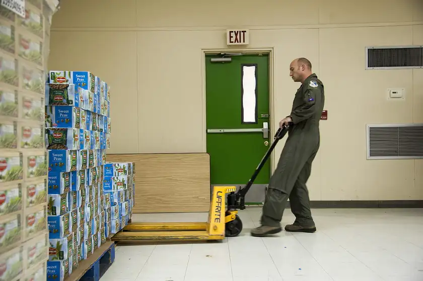 Two men moving a pallet of canned food on a truck lift