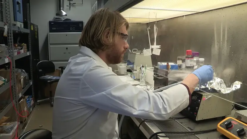 A scientist in a white coat working at a laboratory bench