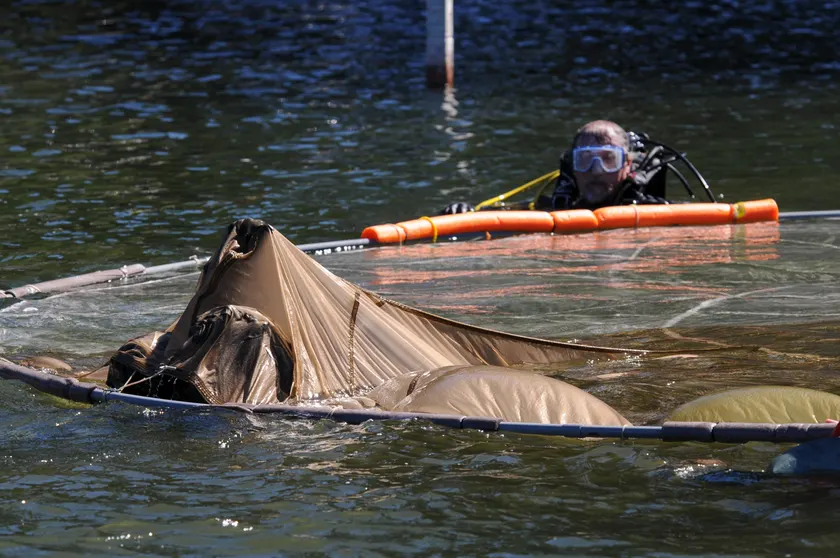 Airmen in uniform swimming and treading water together in a lake