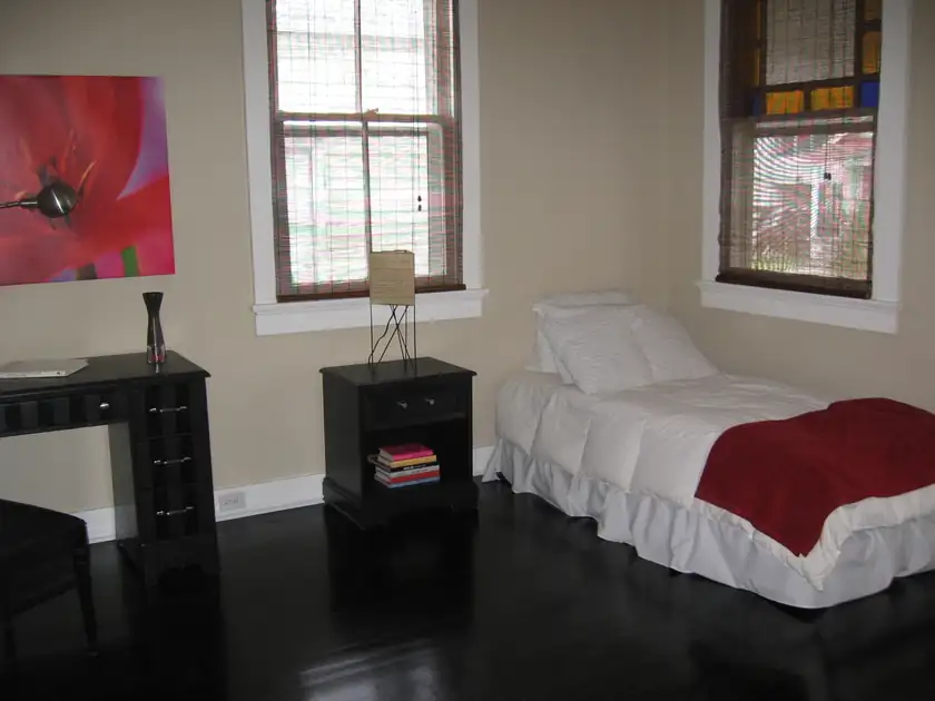 A made bed with white linens in a simply furnished bedroom