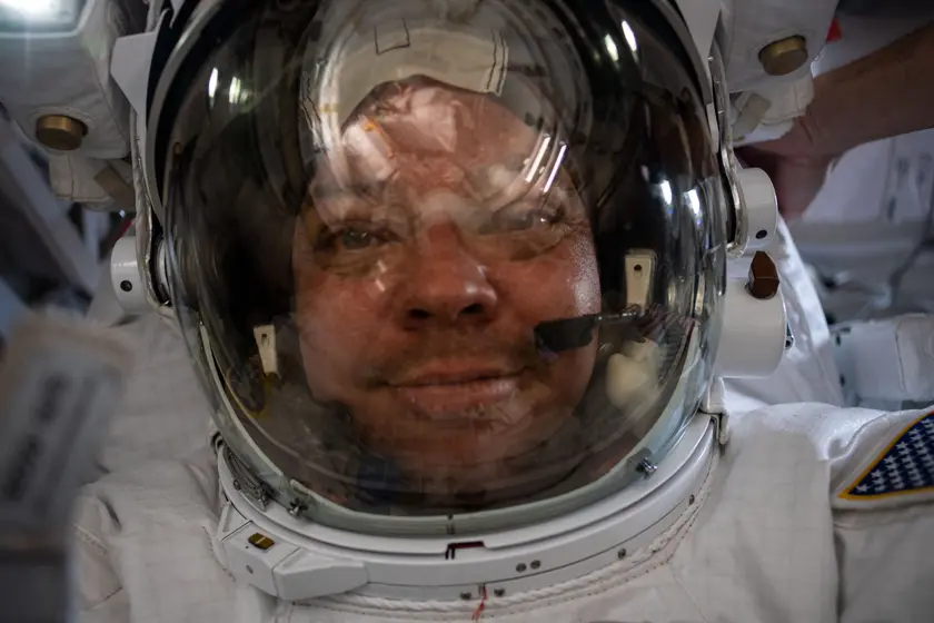 An astronaut in a white spacesuit taking a photo during a spacewalk