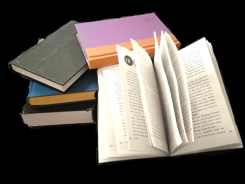 A stack of hardcover books piled on a wooden table