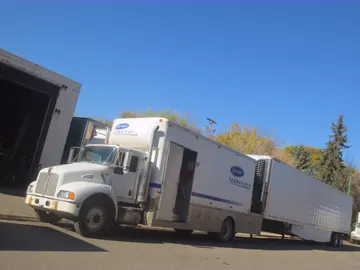 A white refrigerated trailer with a cooling unit parked on pavement