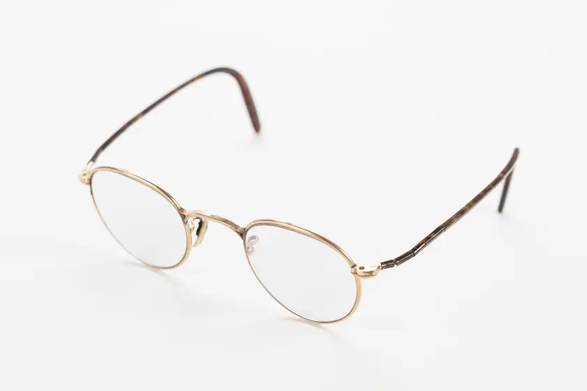 A pair of historic round eyeglasses on a plain background
