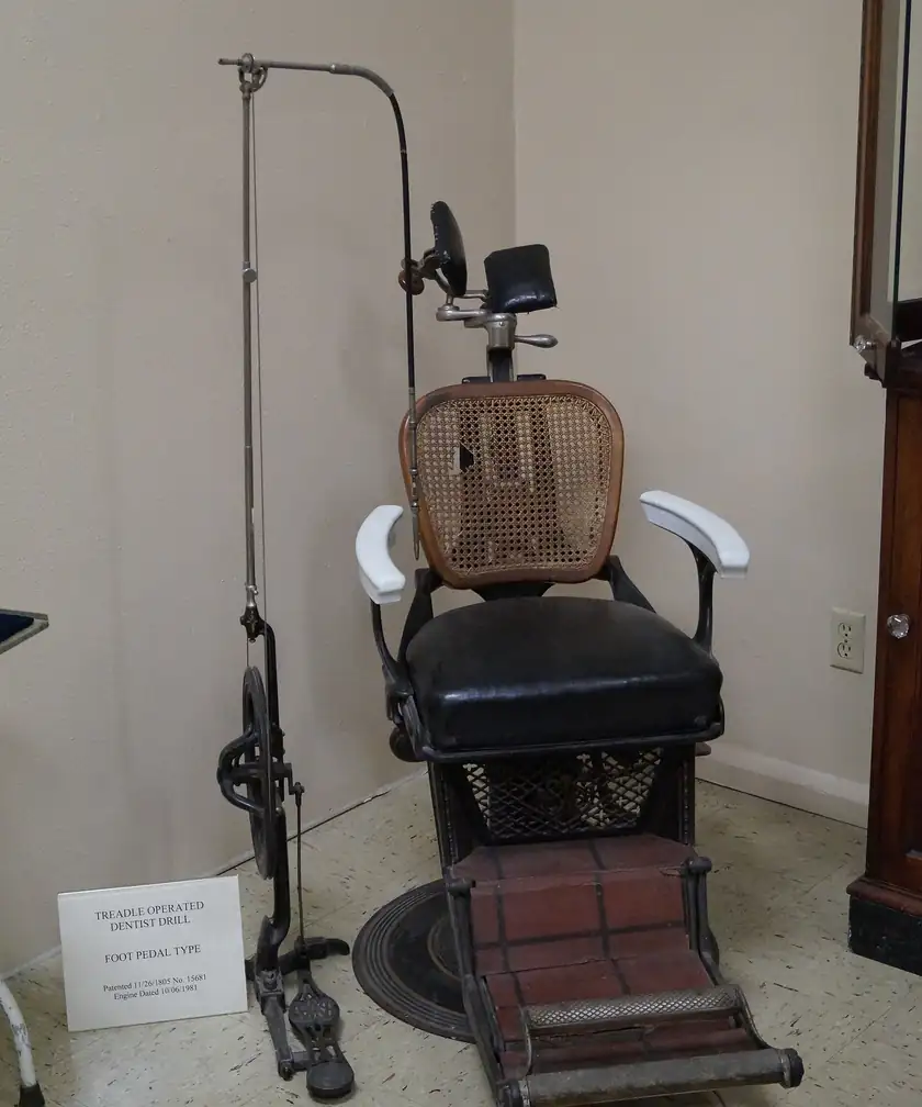 A vintage dental chair and wooden cabinet in a museum display