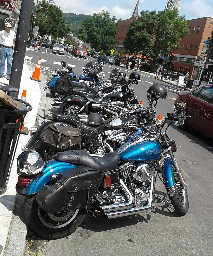 A row of parked motorcycles along a small-city street, with no riders