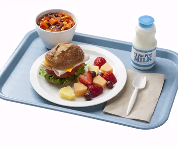 A compartmented school lunch tray with fruit, vegetables, and other dishes
