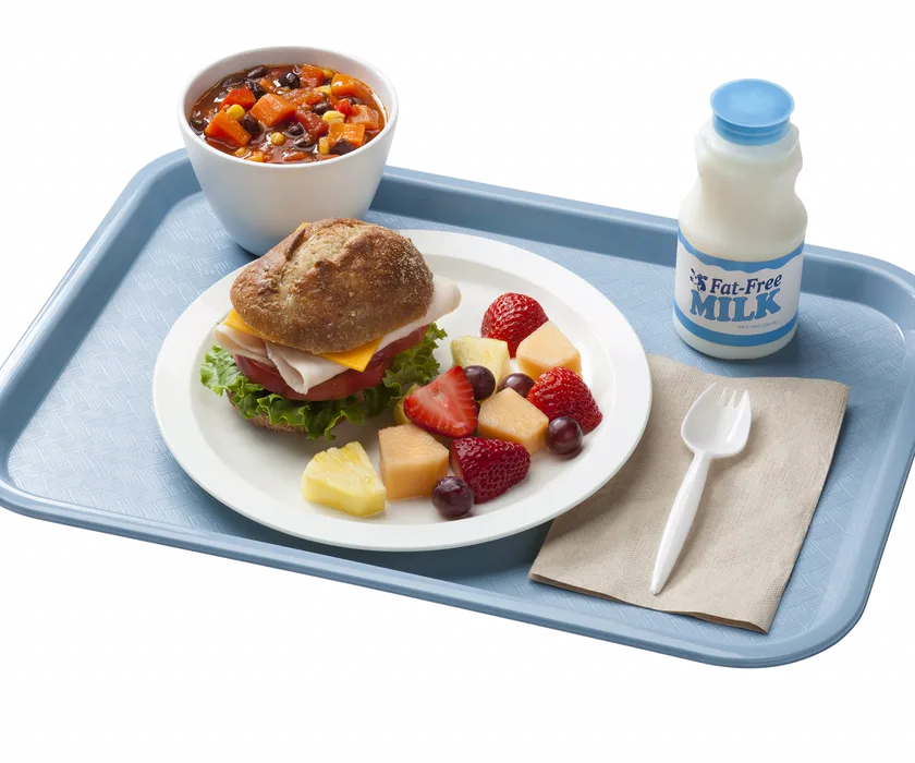 A compartmented school lunch tray with fruit, vegetables, and other dishes