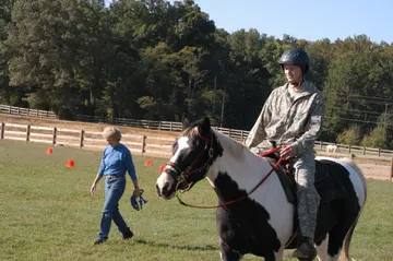 A person riding a horse during a therapy session outdoors