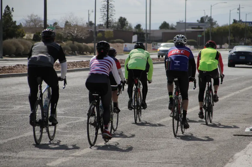 Cyclists riding away from the camera down a paved road