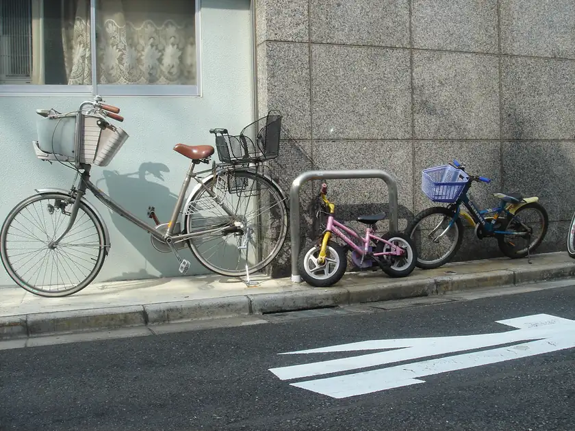 A row of bicycles parked in a rack along a sidewalk, with no riders