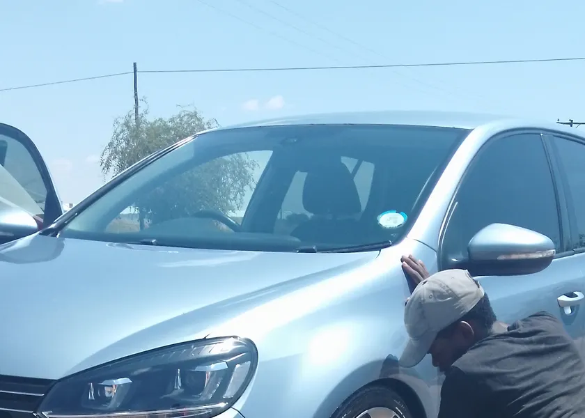 A man kneeling to work on the wheel of a car