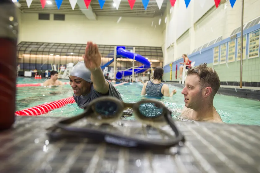 An instructor in a pool supporting an adult who is learning to float