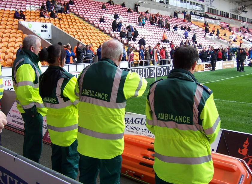 Ambulance crew members in high-visibility jackets standing with a stretcher