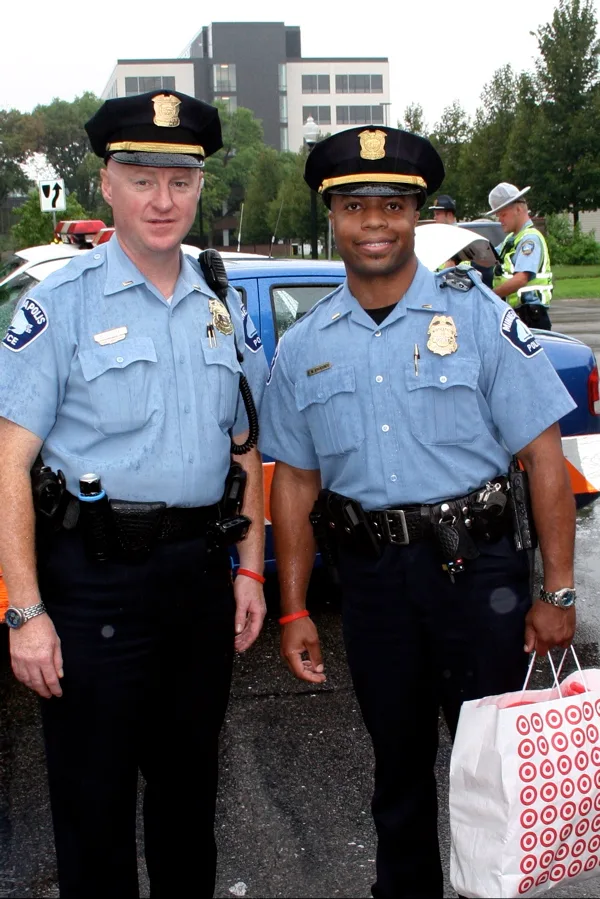 Two police officers in uniform sitting at an outdoor table and talking