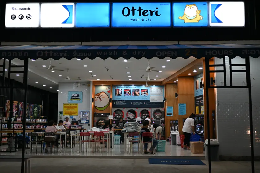 Customers folding laundry inside a lit laundromat at night