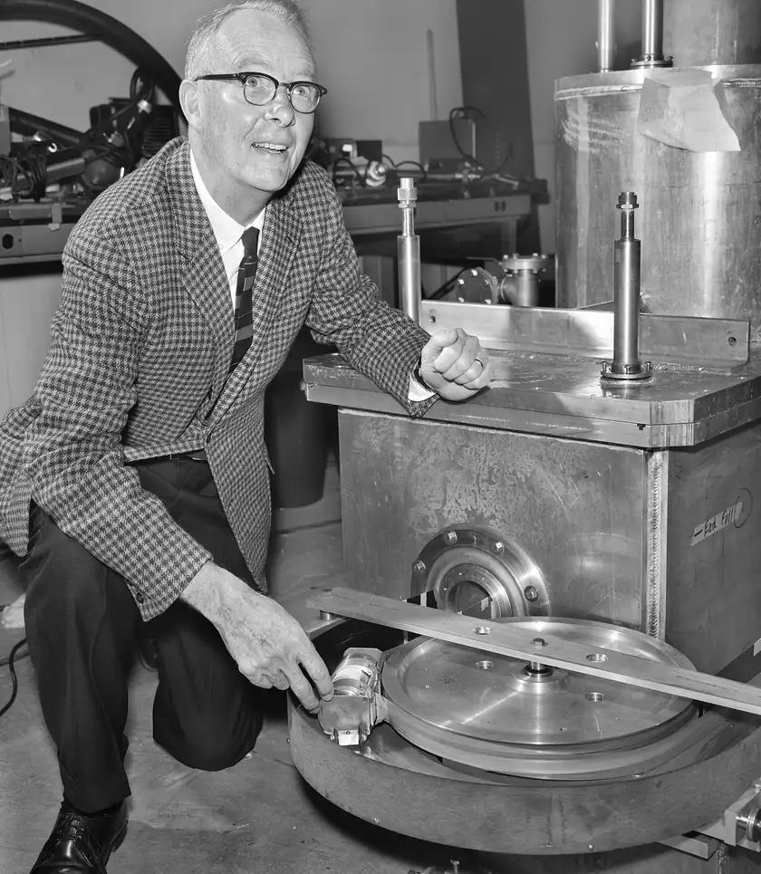 Physicist Luis Alvarez seated beside a large scientific detector