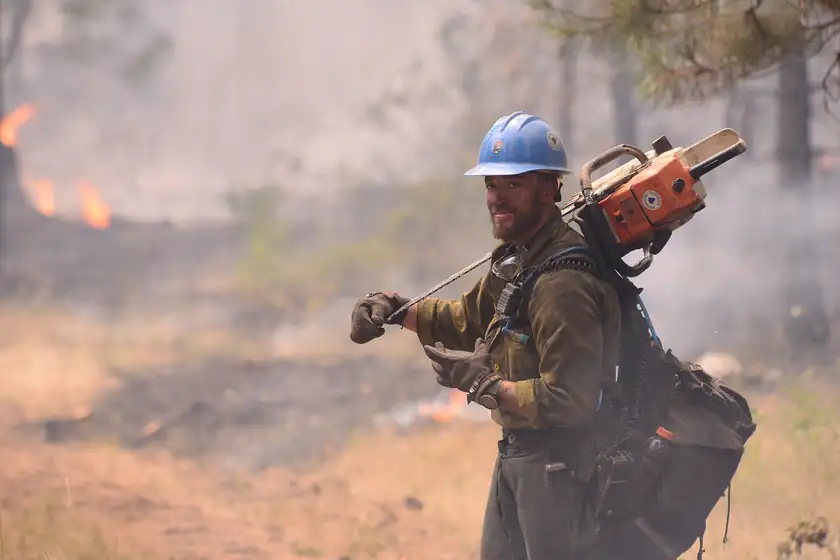 Firefighters in yellow helmets and wildland gear gathered outdoors