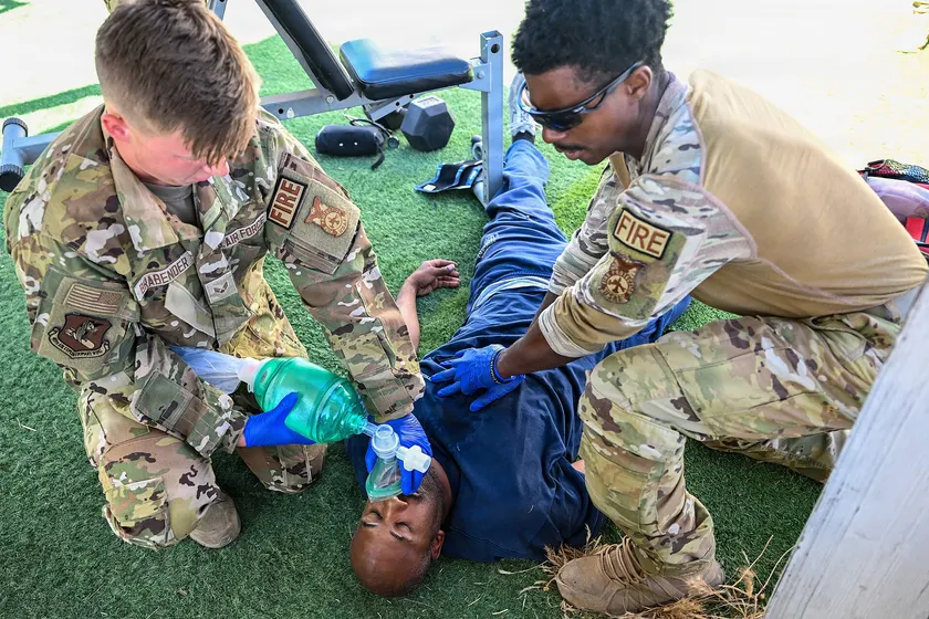 Two firefighters giving rescue breaths with a bag mask during a training exercise