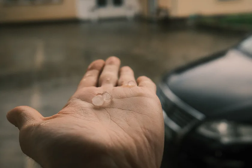 A hand reaching into heavy rain to catch hailstones