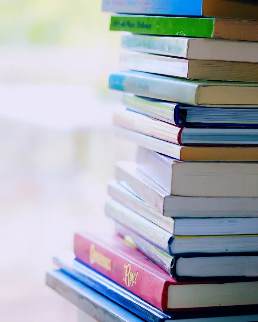 A stack of colorful hardcover books on a white table