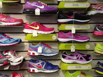 Rows of colorful running shoes lined up on a store display wall