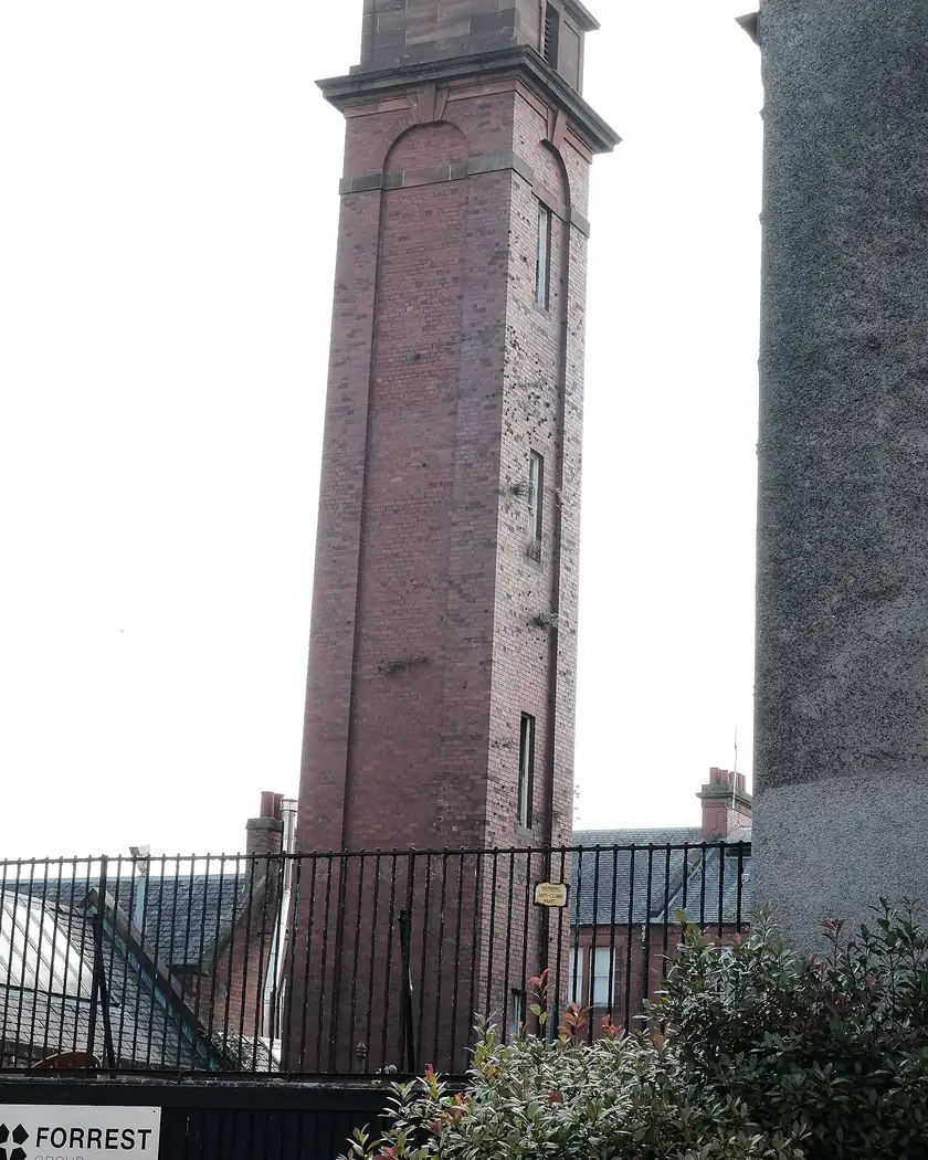 A tall brick hose tower attached to a fire station