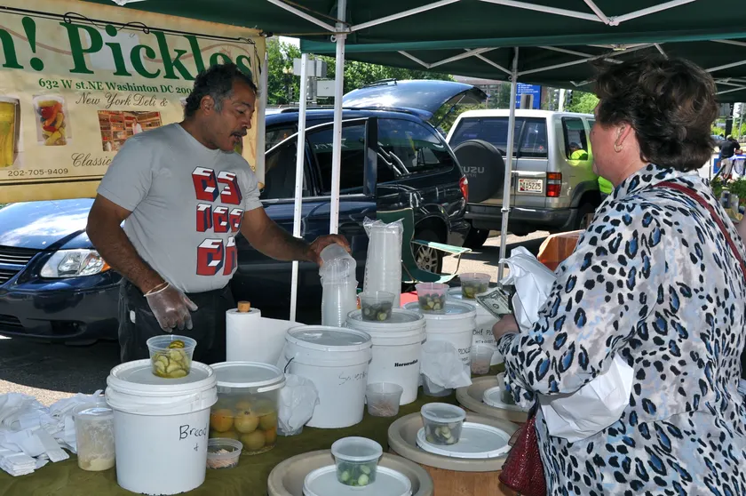 A market vendor serving a customer at a produce stall