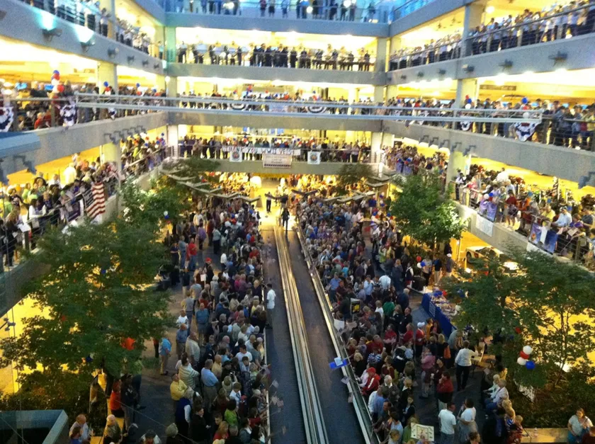 A packed airport atrium with crowds on several balconies lining a welcome-home walkway